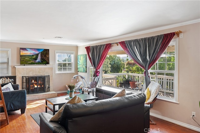 living room featuring ornamental molding, a tile fireplace, and light hardwood / wood-style floors