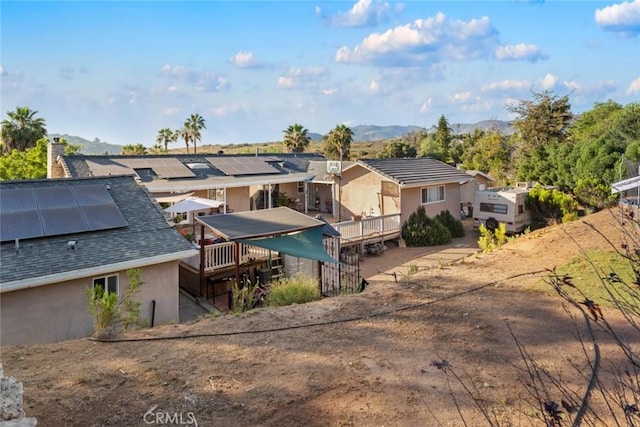 rear view of house with solar panels and a deck with mountain view