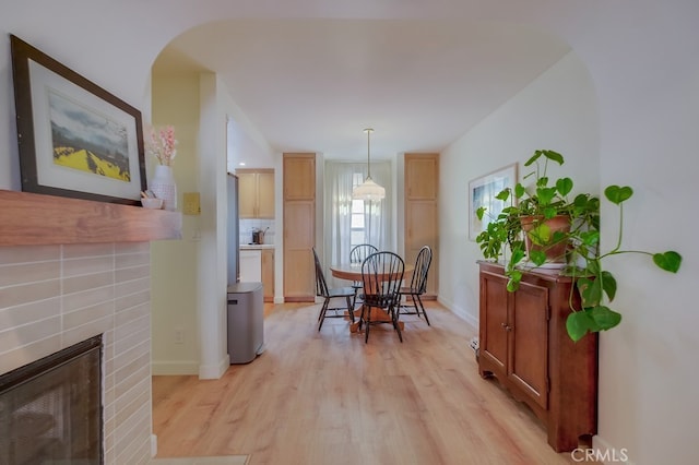 dining area with light wood-type flooring and a brick fireplace