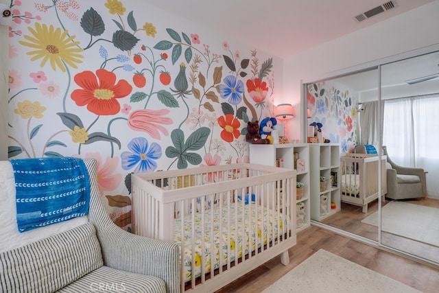 bedroom featuring a nursery area, a closet, and light hardwood / wood-style flooring