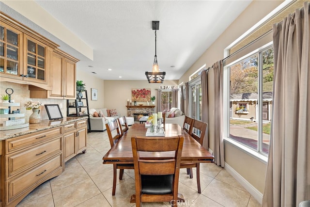 dining space with recessed lighting, light tile patterned flooring, a lit fireplace, and baseboards