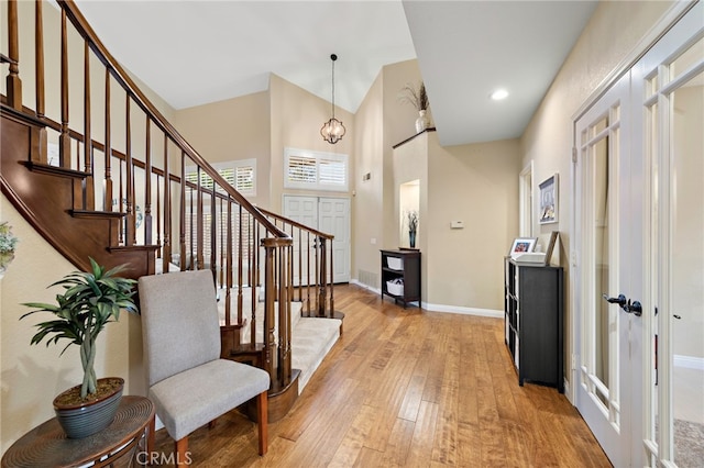 entryway featuring baseboards, a high ceiling, stairs, light wood-style floors, and recessed lighting