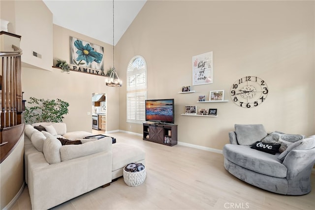 living room featuring visible vents, an inviting chandelier, wood finished floors, high vaulted ceiling, and baseboards