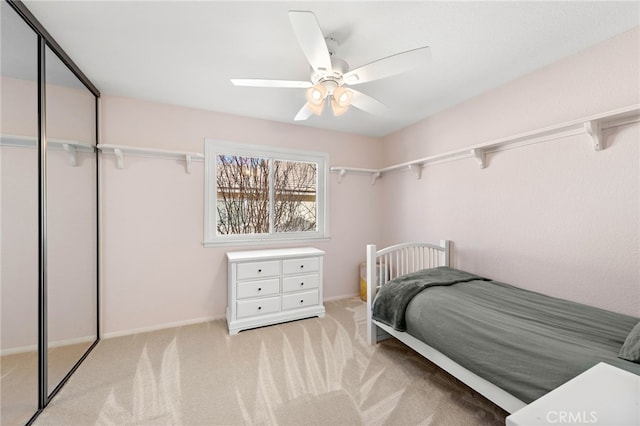 bedroom featuring a ceiling fan, a closet, and light carpet