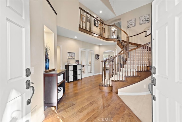 foyer with arched walkways, french doors, stairway, a high ceiling, and wood finished floors