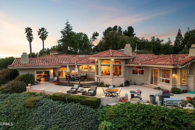 back house at dusk with a patio area and an outdoor hangout area