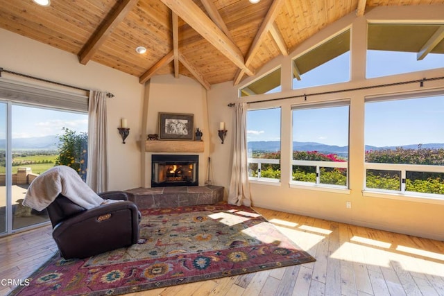 living room with a large fireplace, hardwood / wood-style flooring, high vaulted ceiling, a mountain view, and beam ceiling