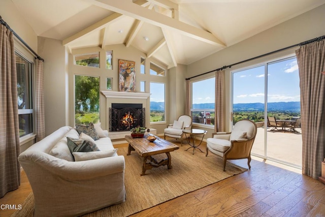 living room featuring a mountain view, light hardwood / wood-style floors, a wealth of natural light, and lofted ceiling with beams