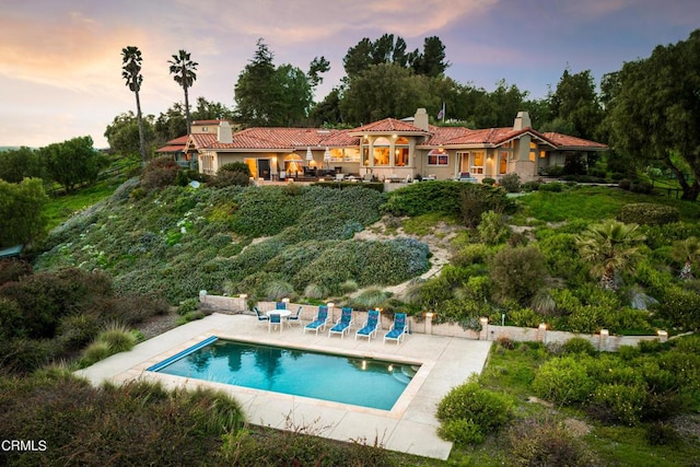 back house at dusk featuring a patio