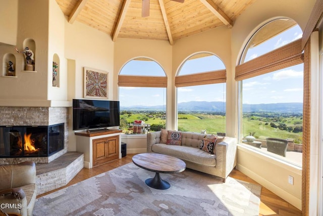 living room featuring beamed ceiling, a fireplace, wood ceiling, and light hardwood / wood-style flooring