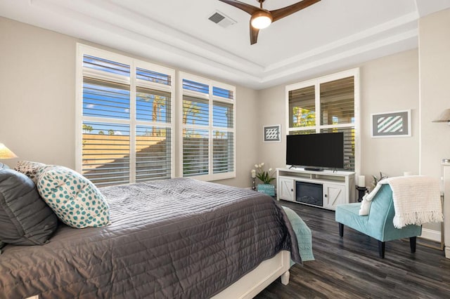 bedroom featuring ceiling fan, dark hardwood / wood-style flooring, and a raised ceiling