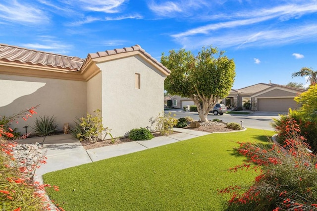 view of home's exterior with a garage and a lawn