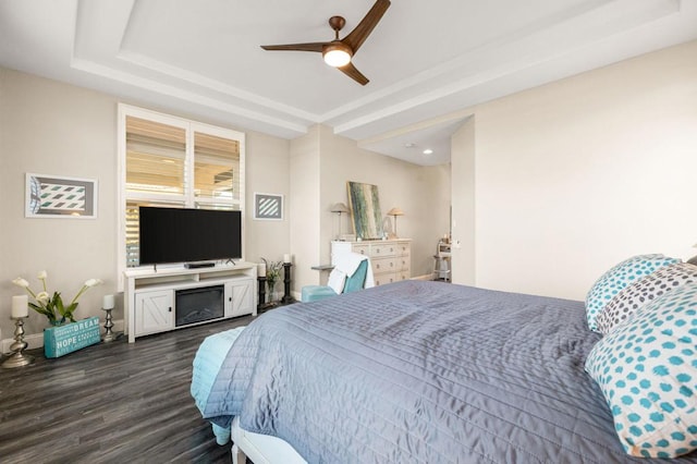 bedroom featuring ceiling fan, dark wood-type flooring, and a raised ceiling