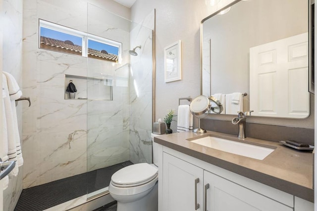 bathroom featuring toilet, a tile shower, and vanity