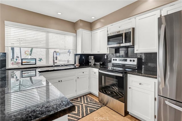 kitchen featuring white cabinets, stainless steel appliances, tasteful backsplash, sink, and light tile patterned flooring