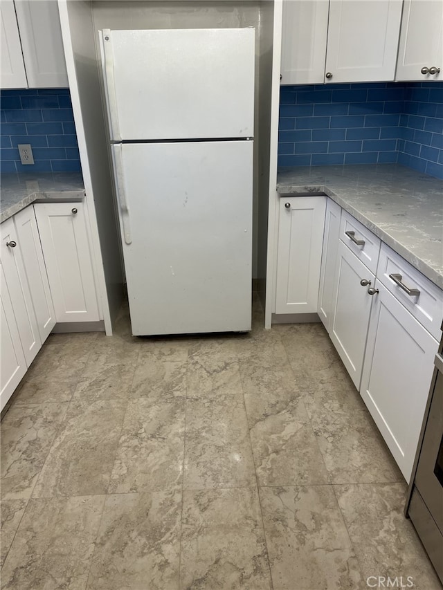 kitchen featuring white fridge, white cabinetry, and decorative backsplash