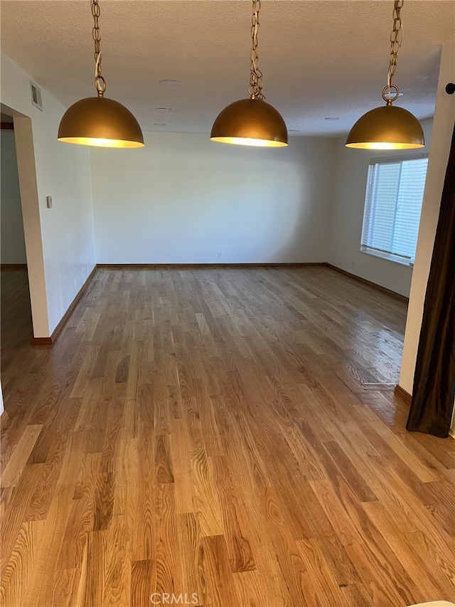 unfurnished dining area featuring a textured ceiling and wood-type flooring