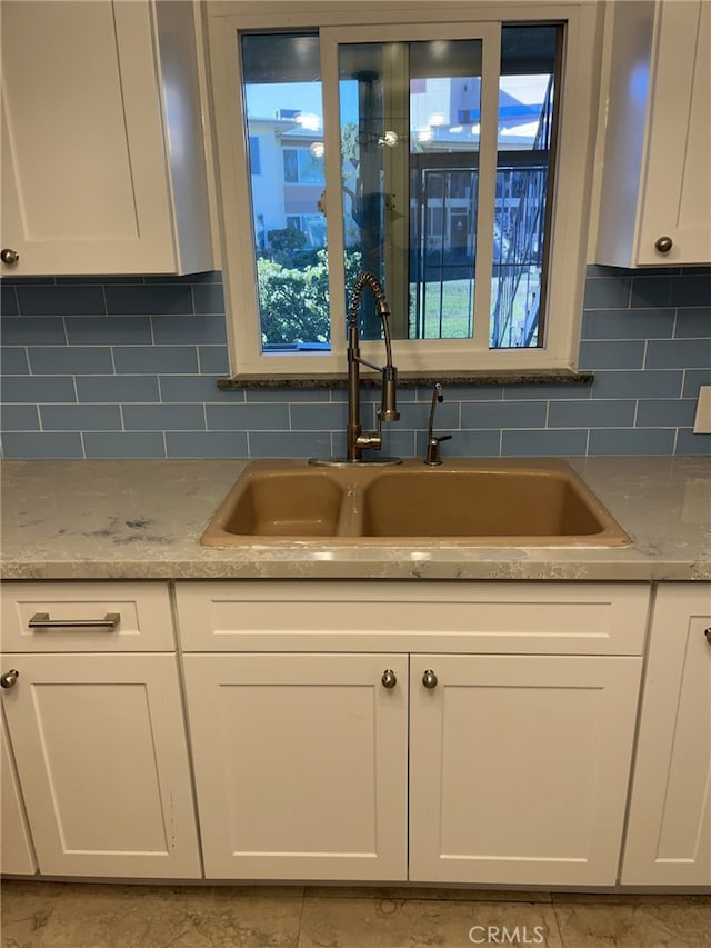 kitchen featuring tasteful backsplash, a healthy amount of sunlight, sink, and white cabinetry