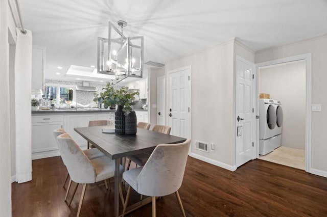 dining room with dark hardwood / wood-style flooring, ornamental molding, an inviting chandelier, and independent washer and dryer