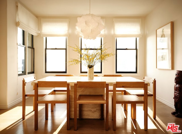 dining area with a wealth of natural light, a notable chandelier, and dark hardwood / wood-style flooring