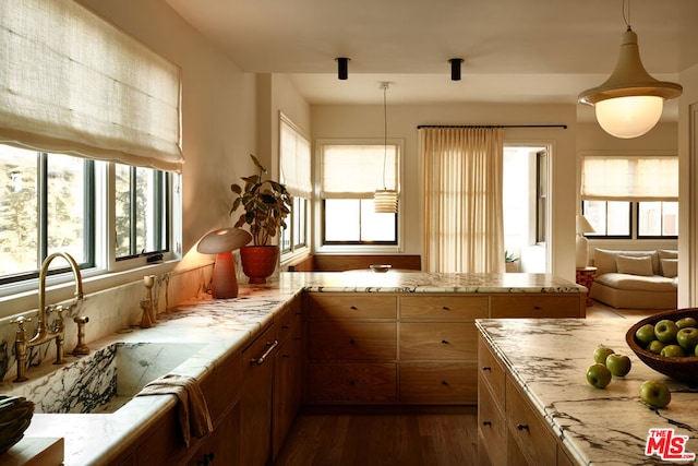 kitchen featuring kitchen peninsula, dark hardwood / wood-style floors, sink, and pendant lighting