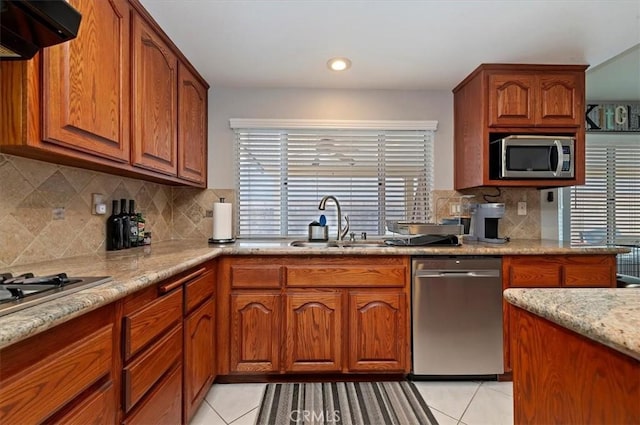 kitchen with exhaust hood, appliances with stainless steel finishes, decorative backsplash, and light stone countertops