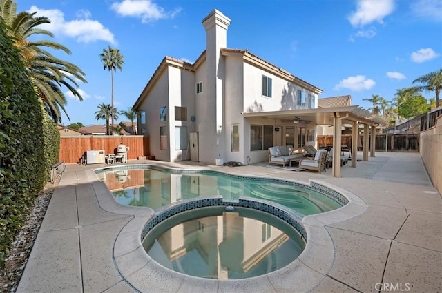 back of property with ceiling fan, a swimming pool with hot tub, outdoor lounge area, and a patio