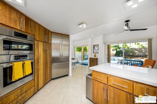 kitchen featuring ceiling fan, a healthy amount of sunlight, stainless steel appliances, and a textured ceiling