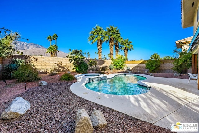 view of swimming pool featuring a patio area, a mountain view, and an in ground hot tub