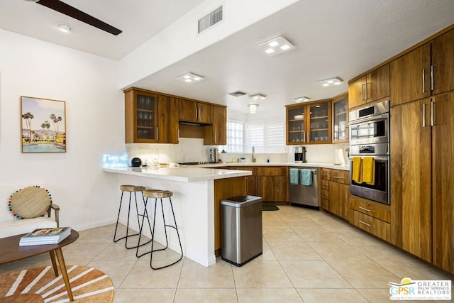 kitchen with kitchen peninsula, stainless steel appliances, a breakfast bar area, and light tile patterned flooring