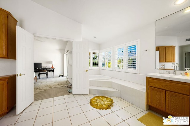 bathroom with tiled bath, lofted ceiling, tile patterned floors, and vanity