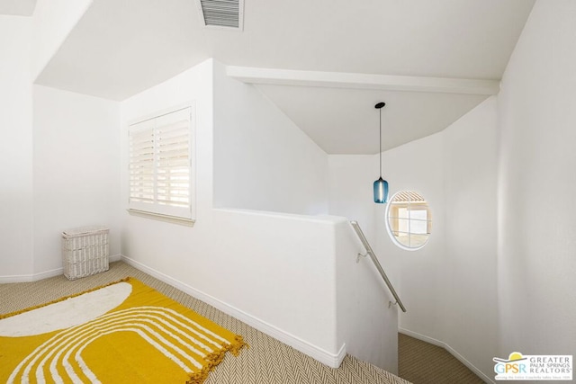 stairway with carpet and beamed ceiling