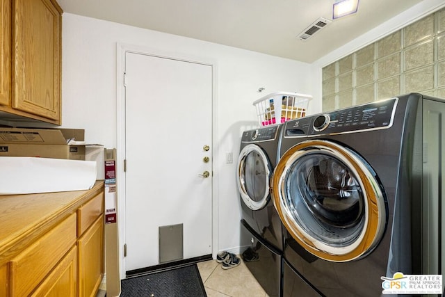 laundry room with washer and dryer, cabinets, and light tile patterned flooring