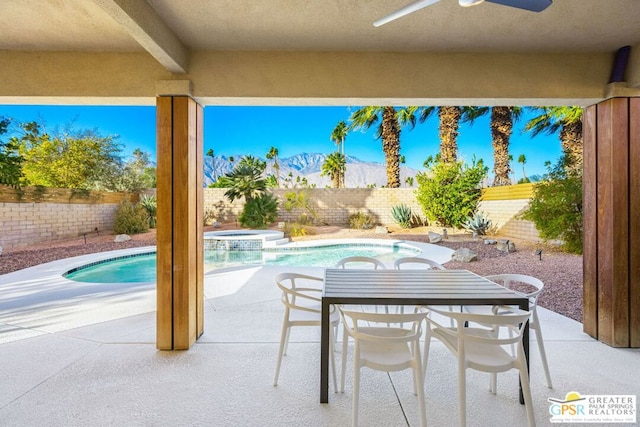 view of patio / terrace with ceiling fan, a swimming pool with hot tub, and a mountain view