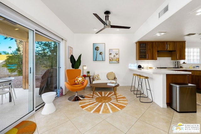 kitchen with ceiling fan, light tile patterned floors, kitchen peninsula, and a breakfast bar area