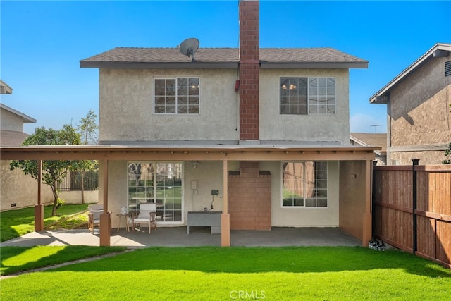 back of property with a yard and a patio