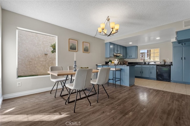 dining room featuring a textured ceiling, a chandelier, light hardwood / wood-style flooring, and sink