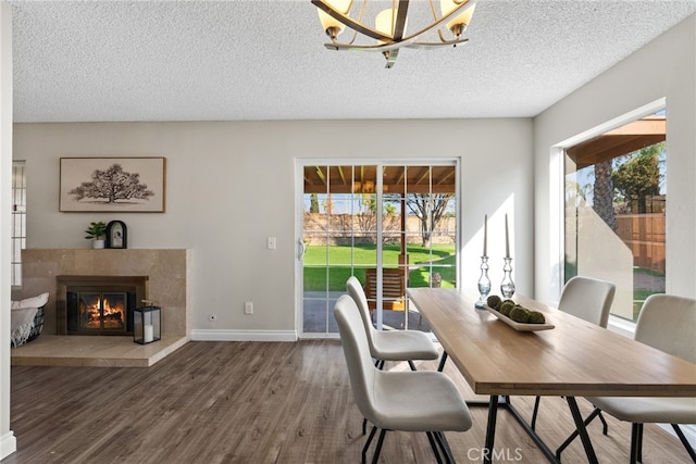 dining area featuring dark wood-type flooring, a high end fireplace, an inviting chandelier, and a textured ceiling