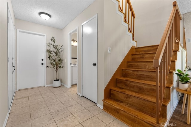 foyer entrance featuring a textured ceiling and light tile patterned flooring