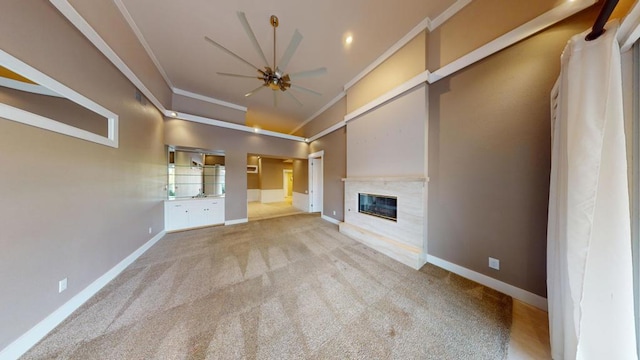 unfurnished living room with ceiling fan, a premium fireplace, crown molding, and carpet flooring