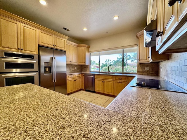 kitchen with backsplash, appliances with stainless steel finishes, extractor fan, and light tile patterned flooring