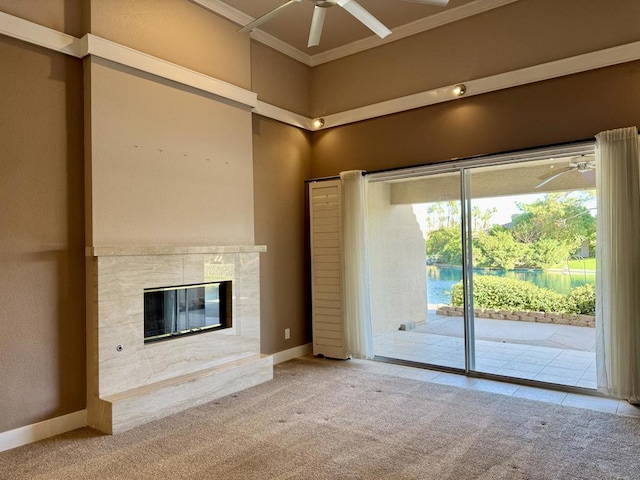 unfurnished living room with ceiling fan, carpet, a towering ceiling, and a tiled fireplace