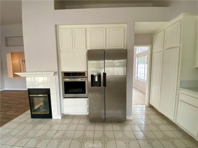 kitchen featuring white cabinetry, a tile fireplace, and stainless steel appliances