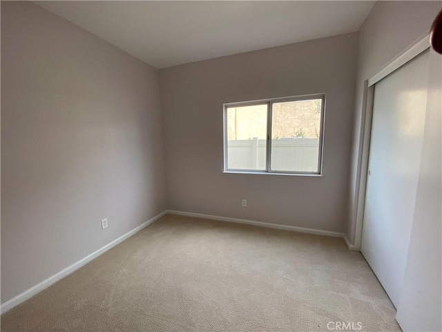 unfurnished bedroom featuring light carpet and a closet