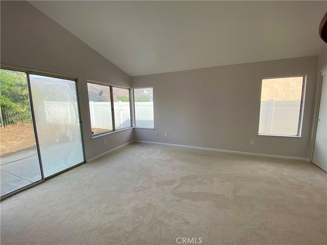 carpeted spare room featuring vaulted ceiling