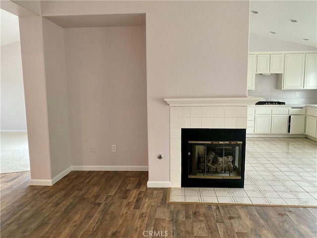 interior details featuring gas stovetop, hardwood / wood-style floors, and a tiled fireplace