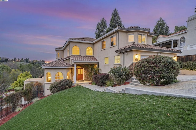 mediterranean / spanish-style home featuring a garage and a lawn