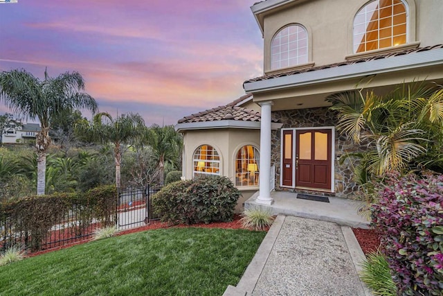 exterior entry at dusk featuring a yard