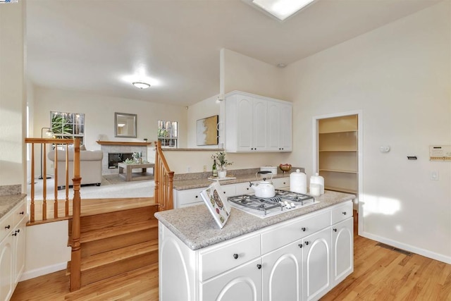 kitchen featuring light hardwood / wood-style floors, stainless steel gas cooktop, white cabinets, and a center island