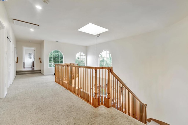 hall with light carpet and a skylight